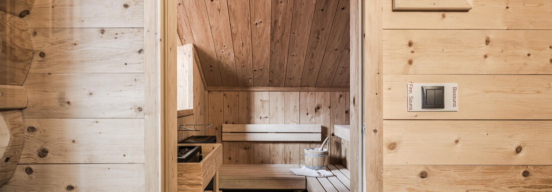 A cozy sauna with wooden paneling and a wooden bench. The room is warm and inviting. - Chalet Resort Sölden - Sölden
