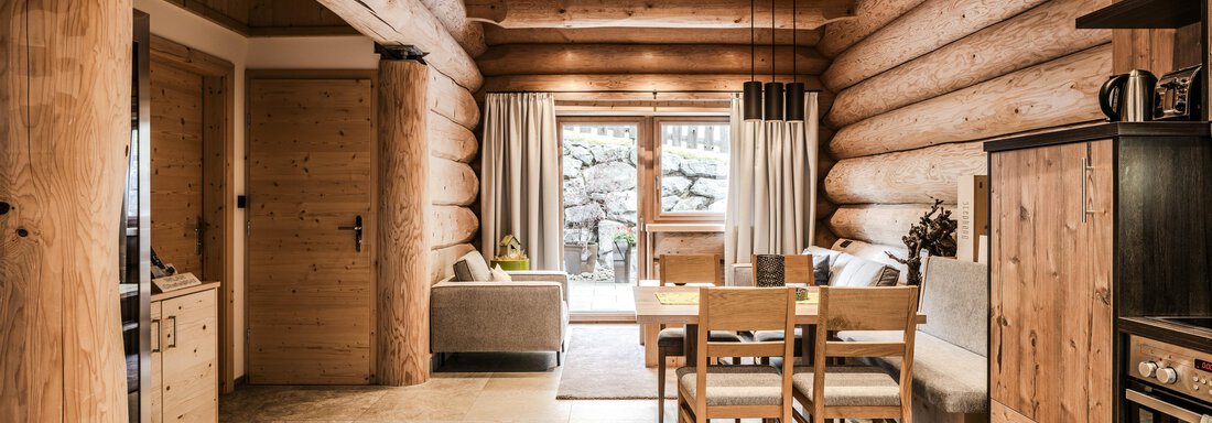 A cozy living space with wooden walls and large windows. The room is modernly furnished and offers a view of nature. - Chalet Resort Sölden - Sölden