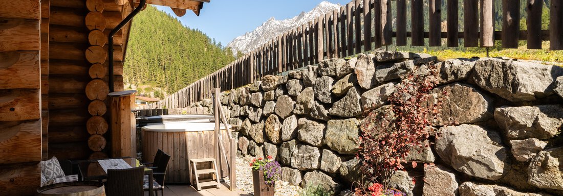 A cozy terrace with a wooden structure and garden chairs. In the background, rocks and majestic mountains can be seen. - Chalet Resort Sölden - Sölden