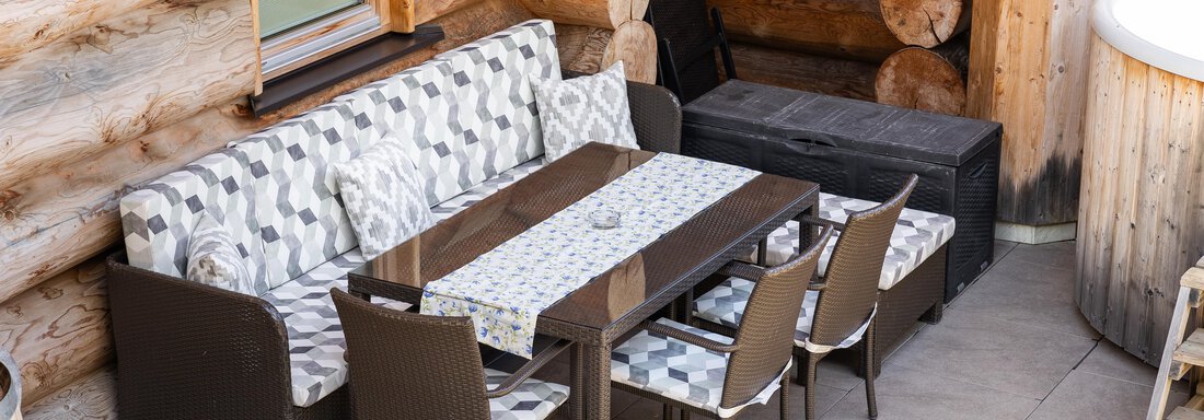 A cozy outdoor dining area with a couch and a large table. Surrounded by wooden walls, the decor creates an inviting atmosphere. - Chalet Resort Sölden - Sölden