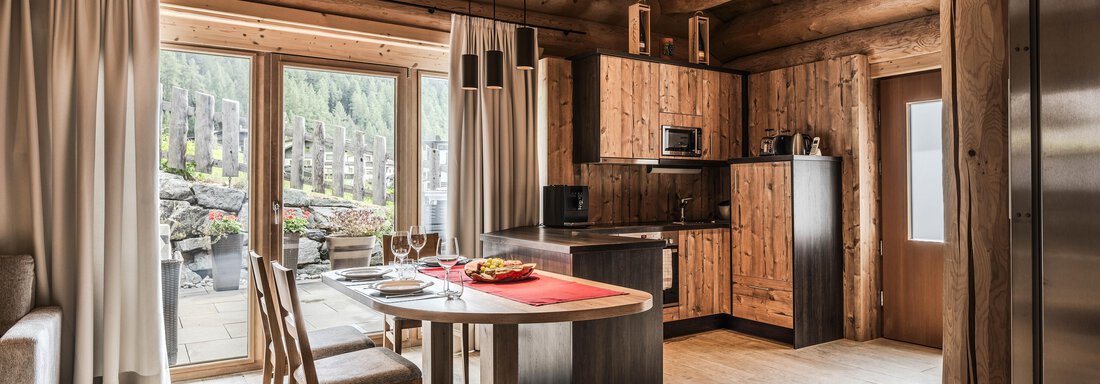 Latschenchalet - gemütliche Wohnküche A modern wooden kitchen with a round table and chairs. Large windows let in plenty of light and offer a view of nature. - Chalet Resort Sölden - Sölden