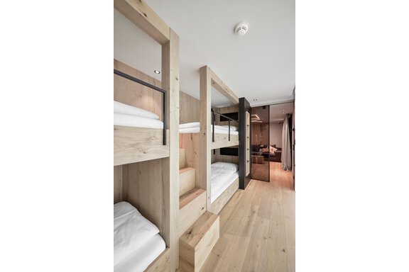A modern dormitory with wooden beds and a bright, minimalist design. The colorful beds are neatly arranged and provide a cozy atmosphere. - Chalet White Pearl by MYALPS - Sölden