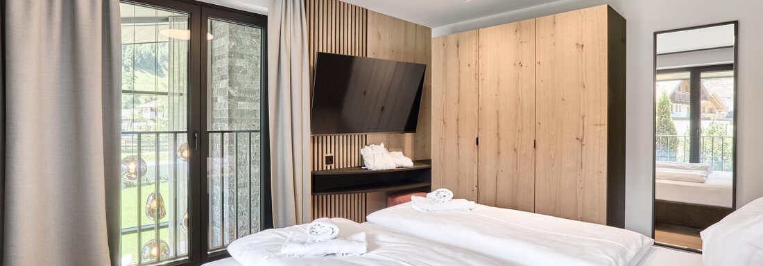 A modern bedroom with two single beds and elegant furnishings. Large windows let in a lot of light and offer a view outside. - Chalet White Pearl by MYALPS - Sölden
