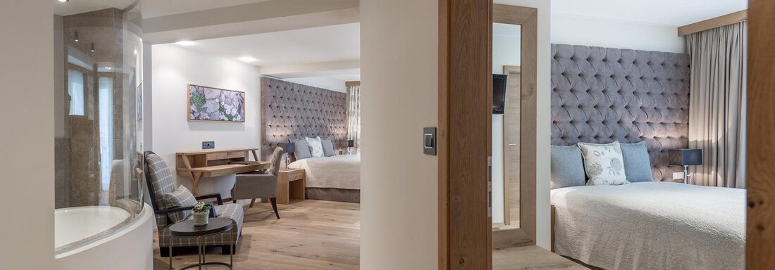 Ein modernes Hotelzimmer mit Holzfußboden und zwei Schlafbereichen. Die Einrichtung ist elegant mit bequemen Möbeln und hellen Farben. - Das Central - Alpine . Luxury . Life - Sölden