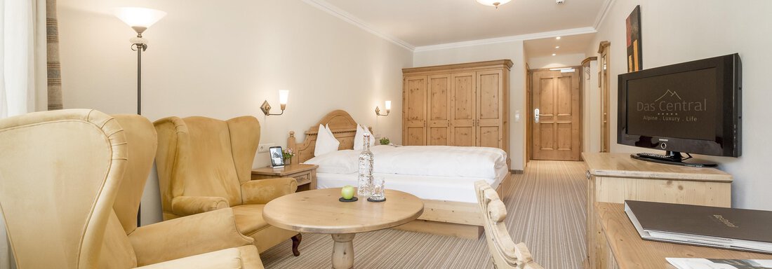 Ein gemütliches Hotelzimmer mit einem komfortablen Bett und einem einladenden Sitzbereich. Der Raum ist hell und modern eingerichtet. - Das Central - Alpine . Luxury . Life - Sölden