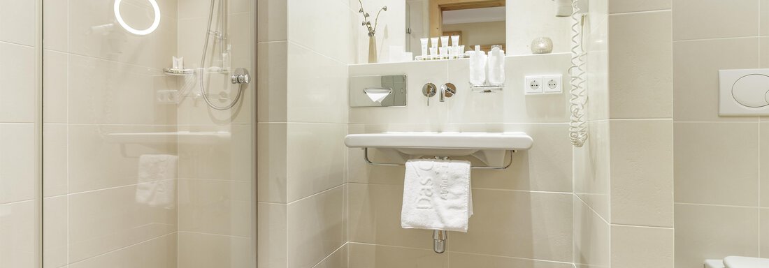 Ein modernes Badezimmer mit einer begehbaren Dusche und eleganten Sanitäranlagen. Die Wände sind hell gefliest und sorgen für eine freundliche Atmosphäre. - Das Central - Alpine . Luxury . Life - Sölden