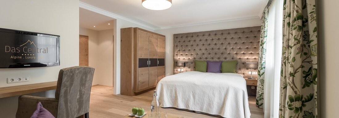 Ein modernes Hotelzimmer mit einem großen Bett und stilvoller Einrichtung. Die Kombination aus warmen Farben und eleganten Details schafft eine einladende Atmosphäre. - Das Central - Alpine . Luxury . Life - Sölden