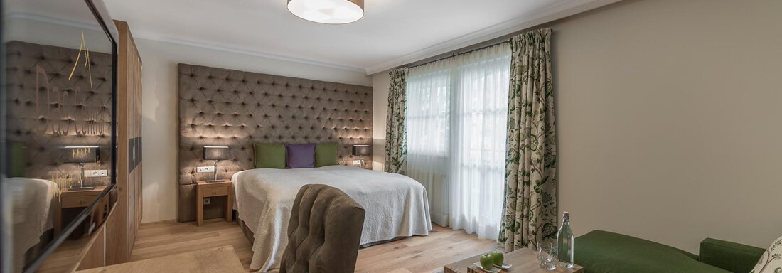 Ein modernes Zimmer mit einem großen Bett und gemütlichem Sitzbereich. Hell erleuchtet von natürlichem Licht und stilvoll dekoriert. - Das Central - Alpine . Luxury . Life - Sölden