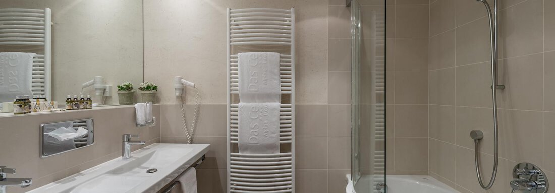 Ein modernes Badezimmer mit einer Badewanne und einer Dusche. Der Raum ist hell und minimalistisch gestaltet. - Das Central - Alpine . Luxury . Life - Sölden