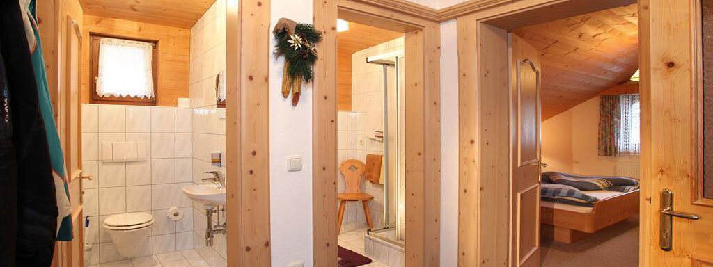 A cozy hallway with two doors leading to a bathroom and a bedroom. The room features wooden elements and a welcoming carpet. - Erbhof - Sölden