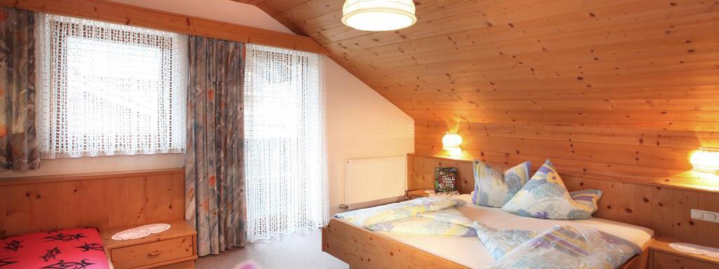 A cozy bedroom with wooden ceilings and two beds. The windows let in plenty of daylight and the decoration is simple and inviting. - Erbhof - Sölden