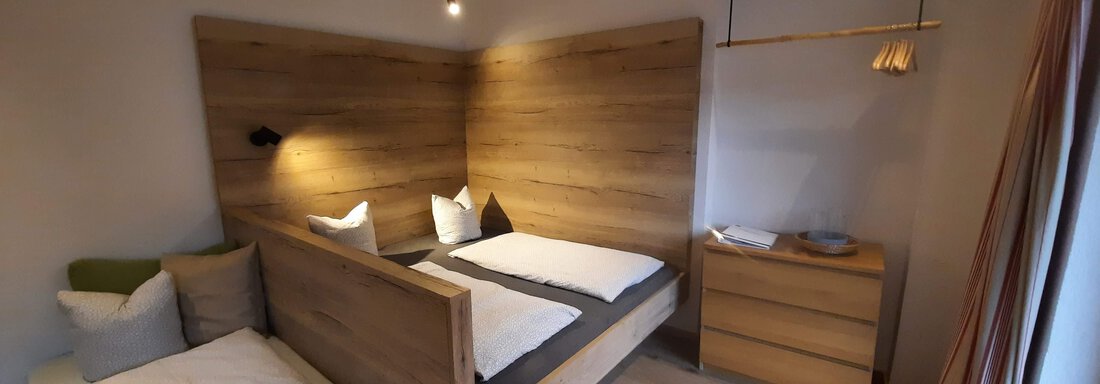 A modern bedroom with two beds and warm wooden elements. Soft lighting creates a cozy atmosphere. - Ferienhaus Anna - Sölden