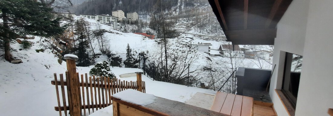 A snowy landscape with mountains in the background and a wooden deck in the foreground. The atmosphere is calm and wintry. - Ferienhaus Anna - Sölden