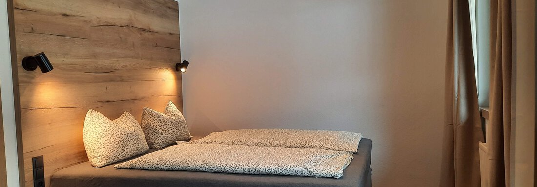 A modern bedroom with a double bed and wooden paneling. Soft lighting and natural materials create a relaxing atmosphere. - Ferienhaus Anna - Sölden