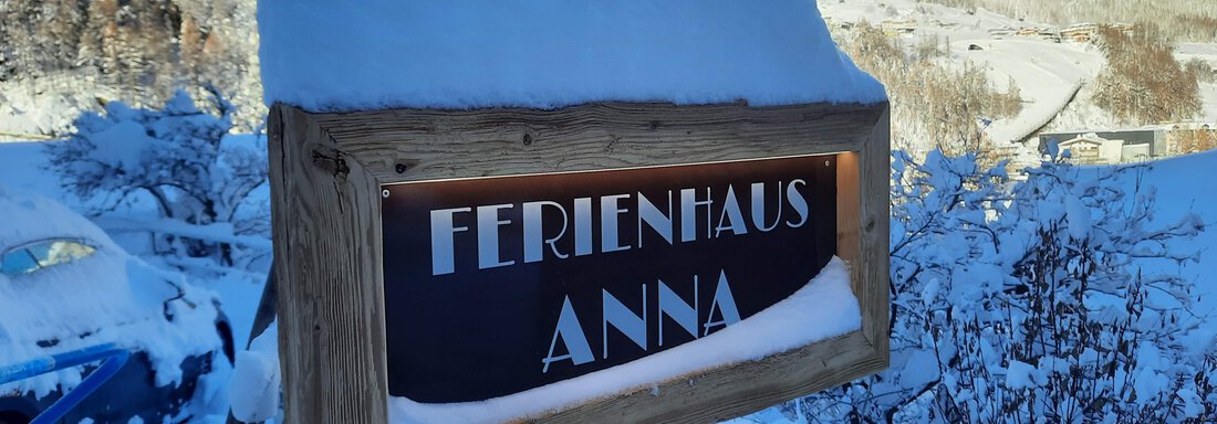 A wooden sign with the inscription "Holiday Home Anna", covered in snow. In the background, snow-covered mountains and a clear winter landscape can be seen. - Ferienhaus Anna - Sölden