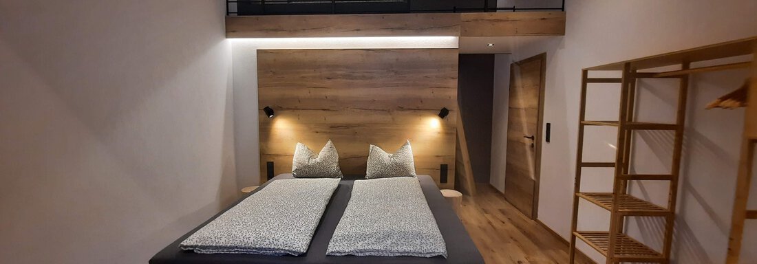A modern bedroom with two single beds and a light wood design. Above, there is a cozy sleeping area. - Ferienhaus Anna - Sölden