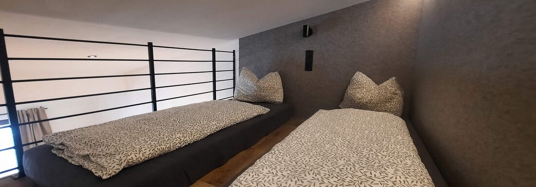 A modern bedroom with two single beds. The walls are in neutral colors and there is an elegant wood finish. - Ferienhaus Anna - Sölden