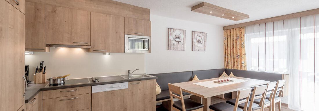 Wohnküche A modern kitchen with wooden cabinets and an inviting dining area. Large windows provide plenty of daylight. - Ferienhaus Apart Sonnzeit - Sölden