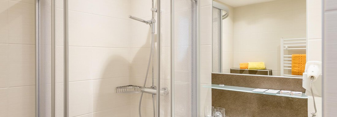 A modern bathroom with a shower cubicle and a sink. The walls are light and there are fresh towels. - Ferienhaus Apart Sonnzeit - Sölden