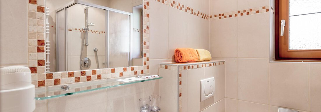A modern bathroom with a shower and a large mirror. There are bright tiles and a small window with daylight. - Ferienhaus Apart Sonnzeit - Sölden