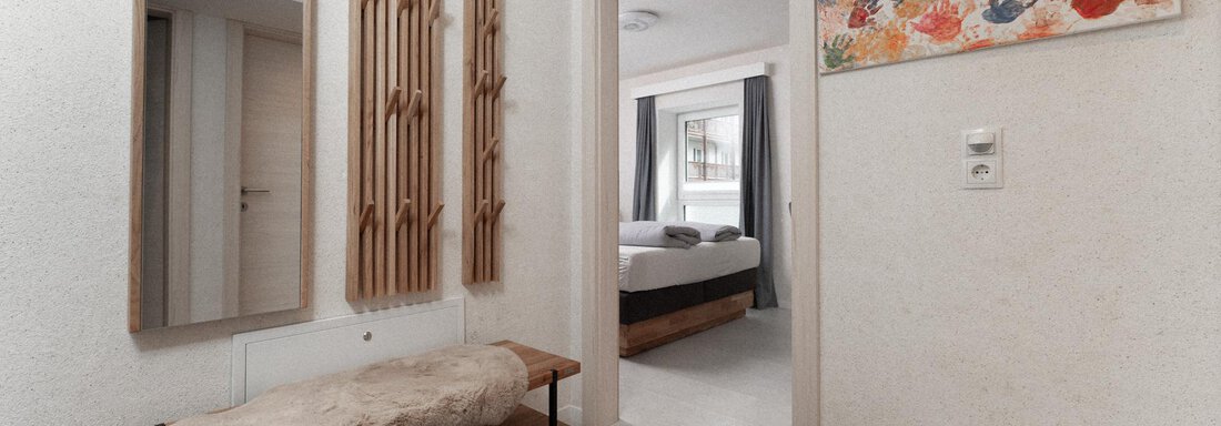 A bright hallway with a modern shoe rack and mirrors on the wall. In the background, a bedroom is visible that looks inviting. - Ferienhaus F2 - Sölden - Sölden