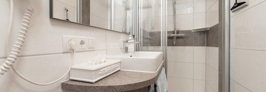 A modern bathroom with a shower and a sink. The walls are tiled in light colors, and the room is well-lit. - Ferienhaus F2 - Sölden - Sölden