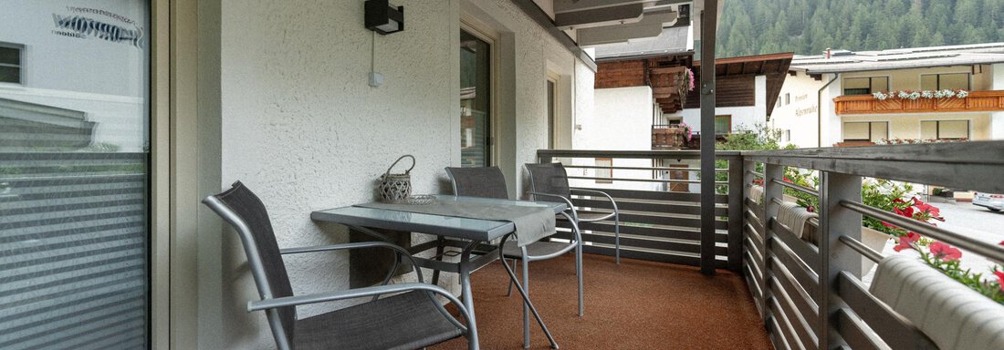 A cozy balcony with two chairs and a table. In the background, green mountains and a tranquil environment are visible. - Ferienhaus F2 - Sölden - Sölden