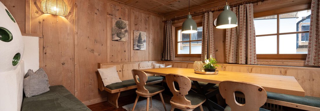 Stube A cozy dining area made of wood with a long table row and comfortable chairs. Large windows let in plenty of daylight and create an inviting atmosphere. - Ferienhaus Valsora - Sölden