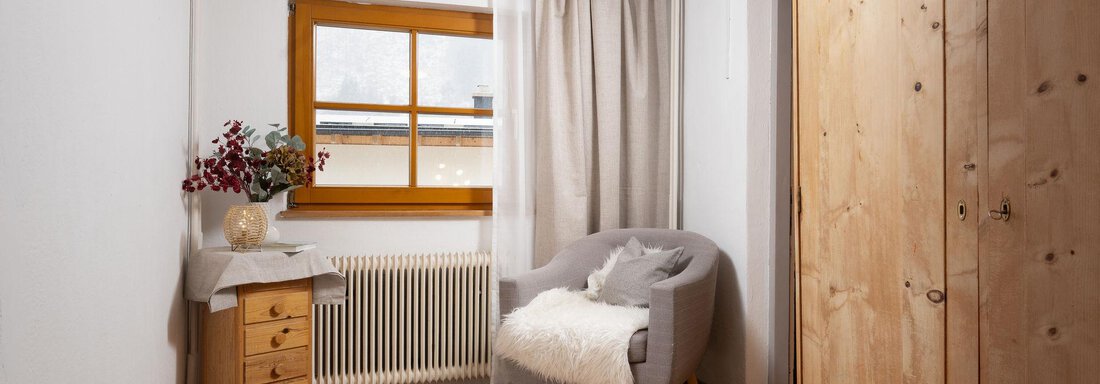 A bright and cozy room with a comfortable chair and a window. A wooden wardrobe and a small chest of drawers complement the decor. - Ferienhaus Valsora - Sölden