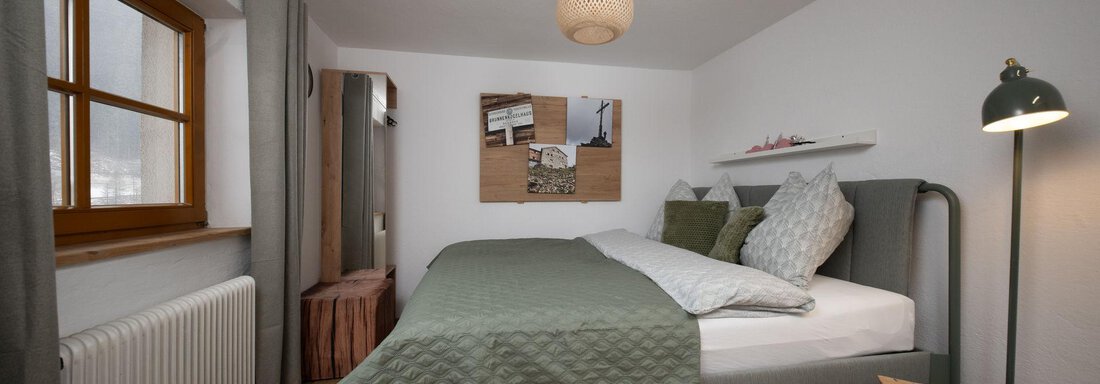 A cozy bedroom with a large bed and bright walls. There is a beautiful wooden floor and natural light coming through the window. - Ferienhaus Valsora - Sölden