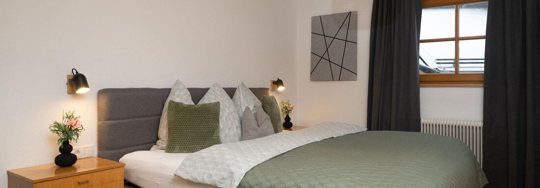 A modern bedroom with a large bed and elegant bedding. The atmosphere is bright and friendly, with a window and decorative elements. - Ferienhaus Valsora - Sölden