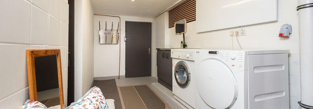 A modern laundry room with a washing machine and dryer. The walls are light and the room is well-lit. - Ferienhaus Valsora - Sölden