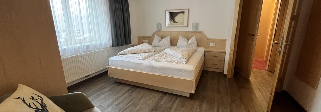 A modern bedroom with two beds and large windows. The room is bright and friendly furnished. - Franzele Appartements & Zimmer - Sölden