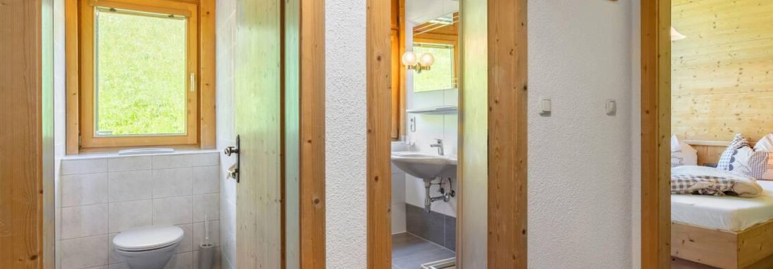 A bright hallway with wooden details and windows. On the left side, there is a bathroom and on the right side, a bedroom. - Garni Nadine - Sölden