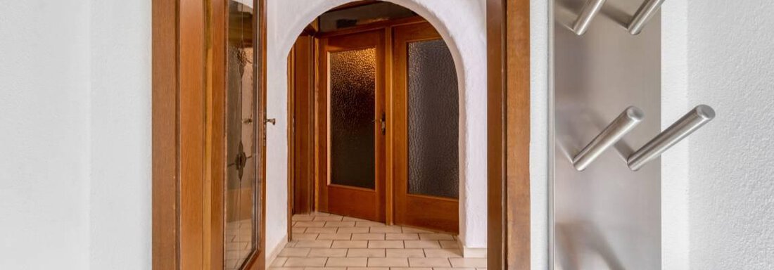 A bright hallway with tiled floor and wooden doors. In the background, a vaulted passage is visible. - Garni Nadine - Sölden