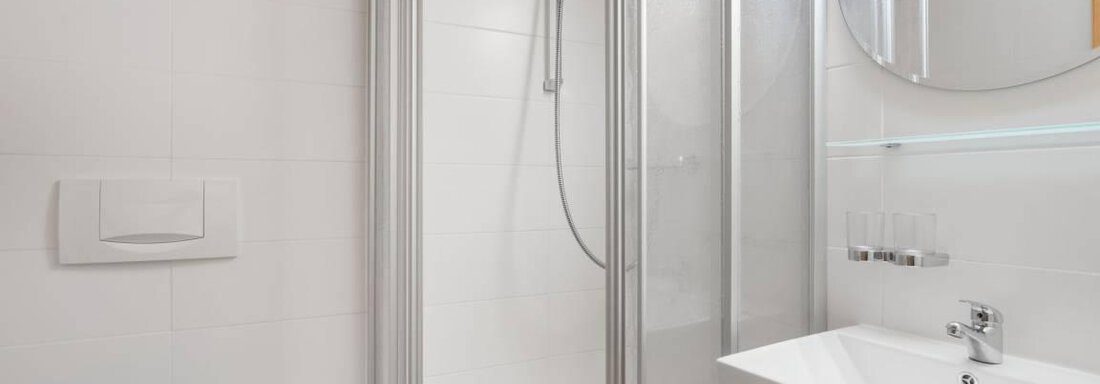 A modern bathroom with a shower and a sink. The floor has a unique design featuring a deer motif. - Garni Nadine - Sölden