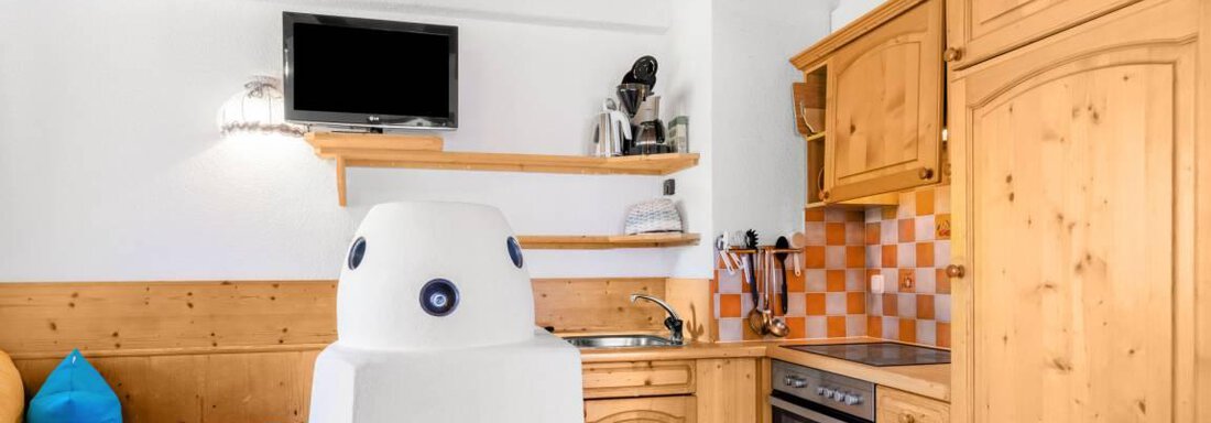 A modern kitchen with wooden cabinets and a bright, cheerful design. The seating area is decorated with colorful cushions and offers a cozy atmosphere. - Garni Nadine - Sölden