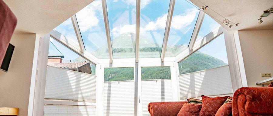 Freier Blick vom Wohnberich in den Sternenhimmel A bright room with large window elements and a view of the mountains. In the foreground is a cozy sofa in a warm color tone. - Garni Nadine - Sölden