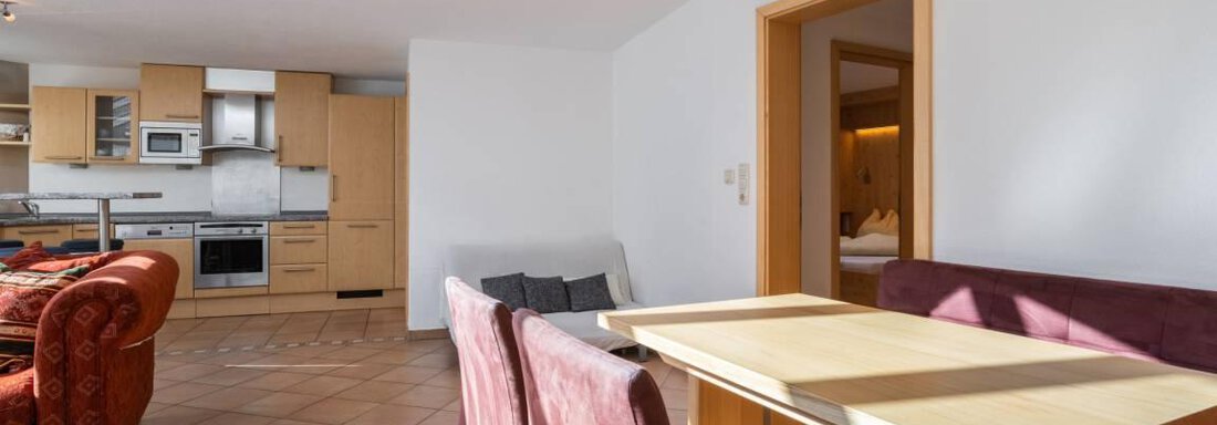 A bright and modern apartment with a dining area and an open kitchen. Large windows provide plenty of daylight. - Garni Nadine - Sölden