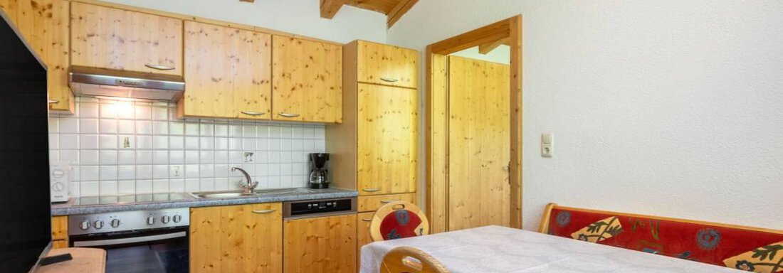 A cozy kitchen with wooden cabinets and a dining table. The room has a warm atmosphere and is well-equipped. - Garni Nadine - Sölden
