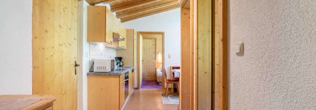 A bright kitchen with wooden cabinets and an inviting hallway. The room has a cozy atmosphere and is well-structured. - Garni Nadine - Sölden