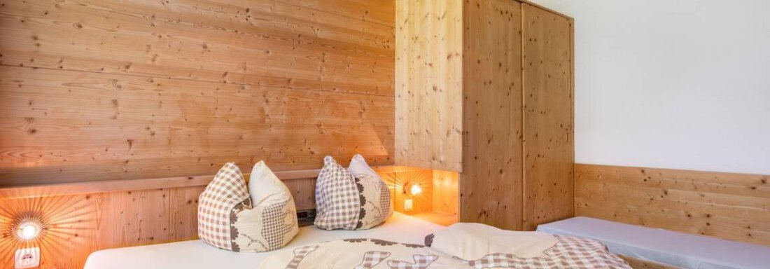 A cozy bedroom with wooden walls and a large bed. The decor is rustic and inviting, perfect for relaxed nights. - Garni Nadine - Sölden