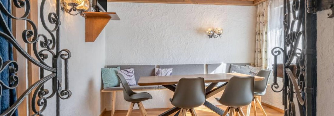 A modernly furnished table with chairs in a bright room. The walls are in neutral colors, and a wooden ceiling creates a cozy atmosphere. - Garni Nadine - Sölden