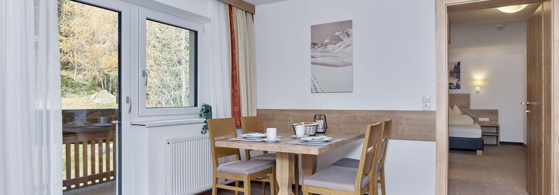 A cozy dining area with a table and chairs. Windows provide a view to the outside and the decor is modern and welcoming. - Gästehaus Bergkristall - Sölden