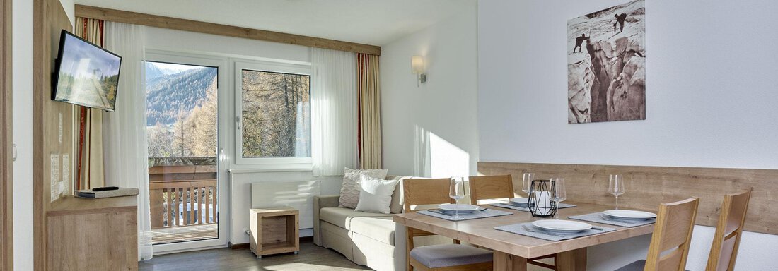 Appartement 2 und 4 A modern living room with a dining table and chairs. Large windows let in plenty of daylight and provide a view of the mountains. - Gästehaus Bergkristall - Sölden