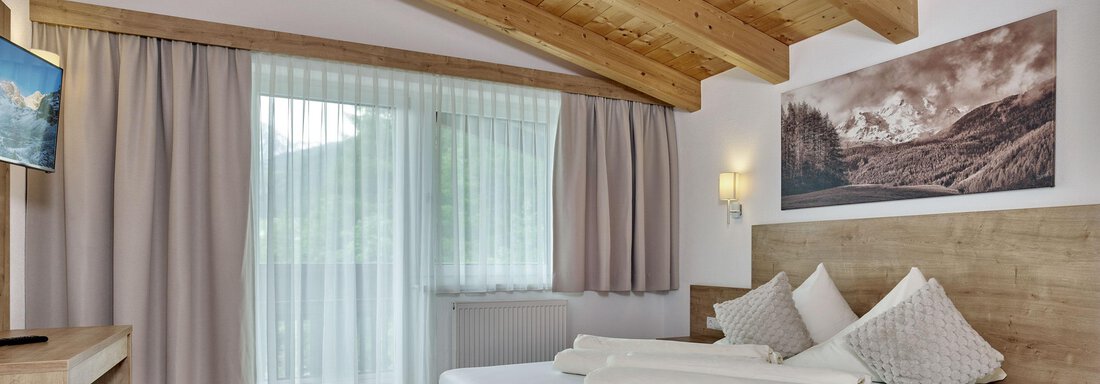 CF058993-2 A modern room with wooden elements and a cozy atmosphere. It offers a large bed, a desk, and a window overlooking nature. - Gästehaus Bergkristall - Sölden