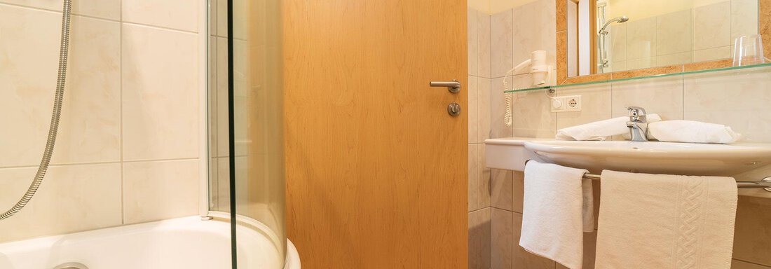 A modern bathroom with a shower, sink, and wooden details. It is bright and clean, ideal for relaxation. - Gästehaus Europa - Sölden