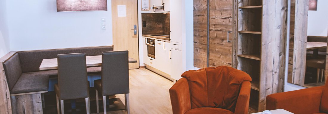A modern living room with a cozy seating area and a dining space. The furnishings are made of wood and provide a bright, pleasant atmosphere. - Gästehaus Europa - Sölden