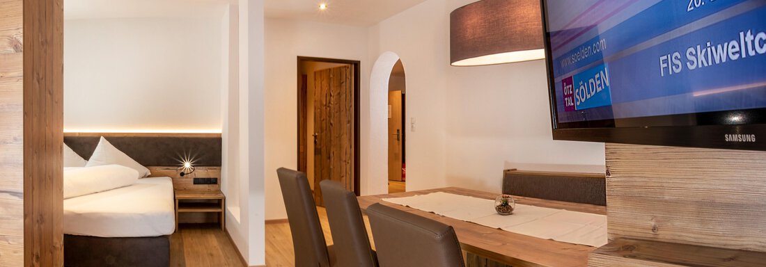 Gstrein_16.2 A modern room with a cozy living area and a large TV. There is a dining area and plenty of natural light. - Gästehaus Europa - Sölden