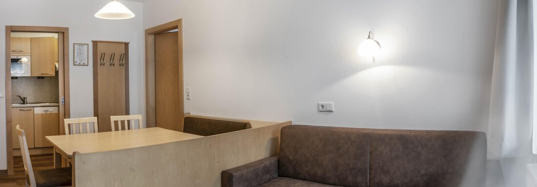 A cozy living space with a table, chairs, and a couch. The walls are bright and the light is friendly. - Gästehaus Europa - Sölden
